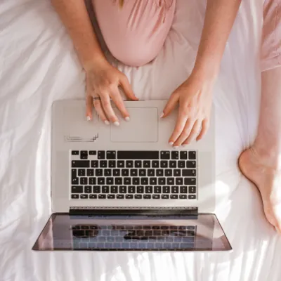 woman browsing for the best porn for women on her laptop in bed
