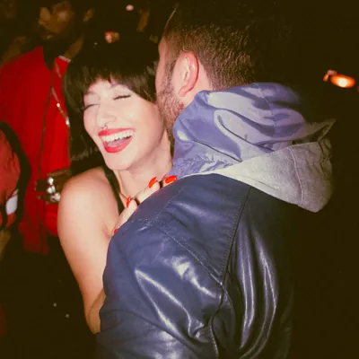 woman laughing in a club as her boyfriend whispers dirty talk in her ear